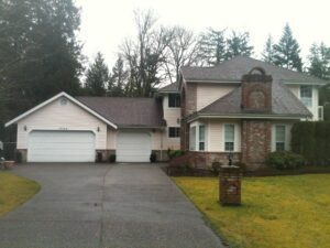 A large house with two cars parked in front of it.