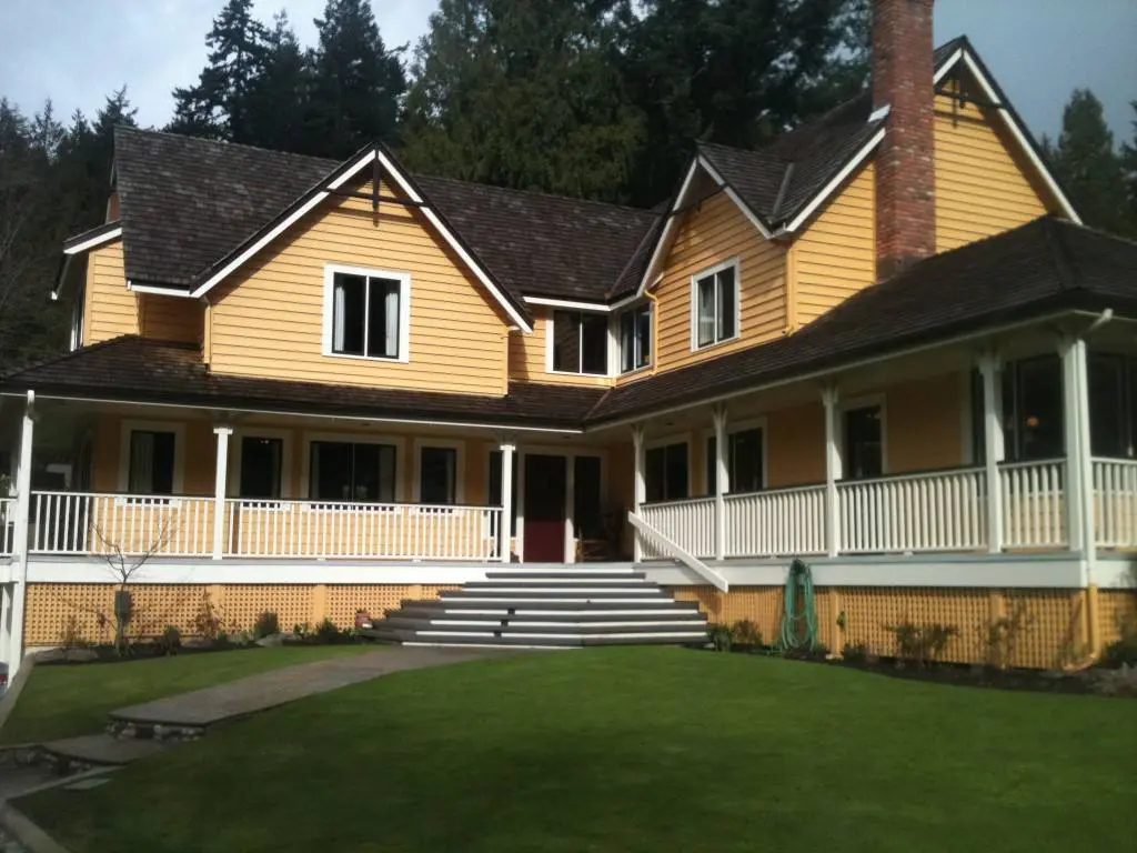 A large yellow house with a porch and lawn.